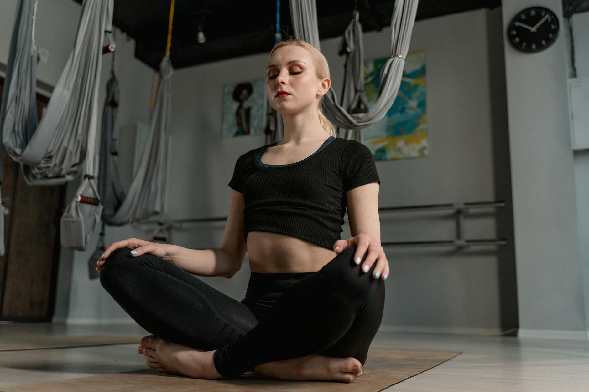 Młoda kobieta medytuje w studiu jogi z linami do aerial jogi