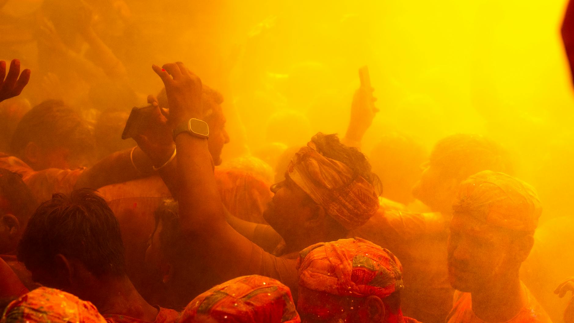 Tłum świętujący Holi w Indiach w chmurze pomarańczowego proszku