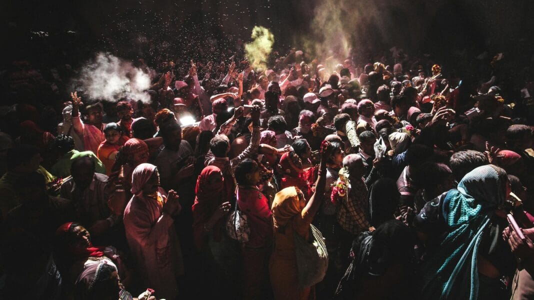 Tłum uczestników świętujących Holi w Indiach w chmurach kolorowych proszków