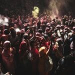 Tłum uczestników świętujących Holi w Indiach w chmurach kolorowych proszków