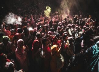Tłum uczestników świętujących Holi w Indiach w chmurach kolorowych proszków