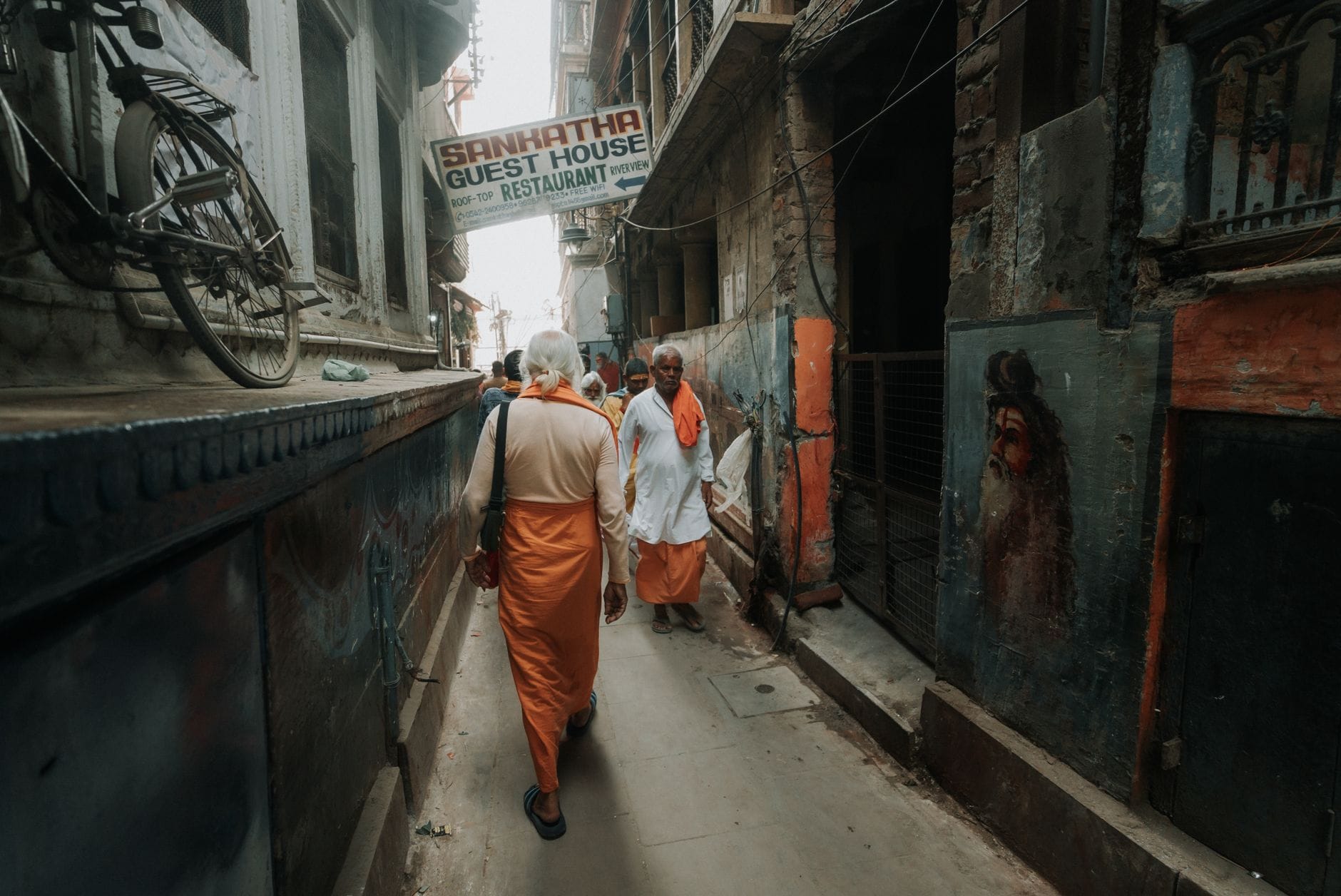 Pielgrzymi na wąskiej uliczce Varanasi z kolorowymi malowidłami ściennymi