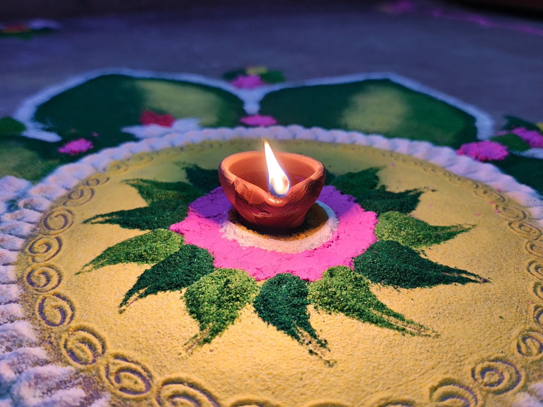 Kolorowa mandala rangoli z zapaloną diyą na święto Diwali Kolorowa mandala rangoli z zapaloną diyą na święto Diwali