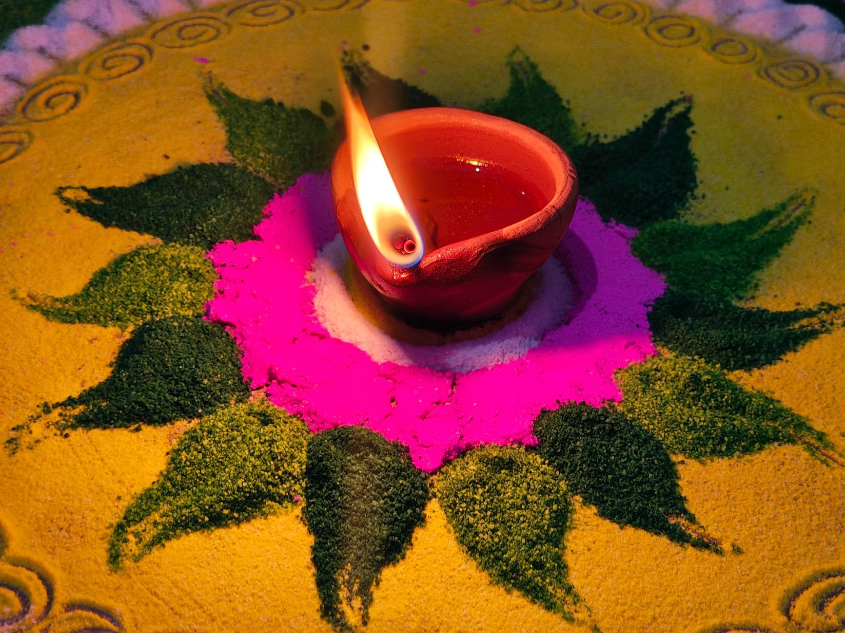 Kolorowe rangoli na Diwali z glinianą lampką oliwną pośrodku