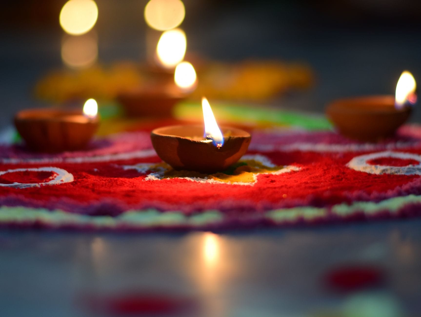 Płonące diyas ustawione na kolorowym wzorze rangoli podczas Diwali